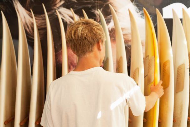 young man looking at surfboards 9887d990